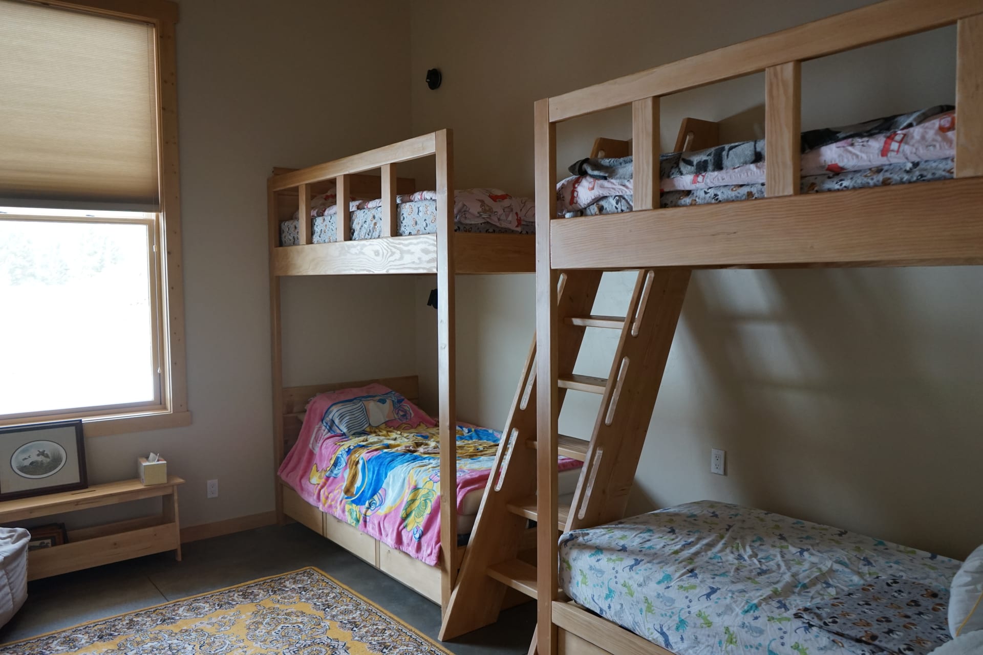 Bunk room with solid oak double bunks, patterned rug, and sunny window