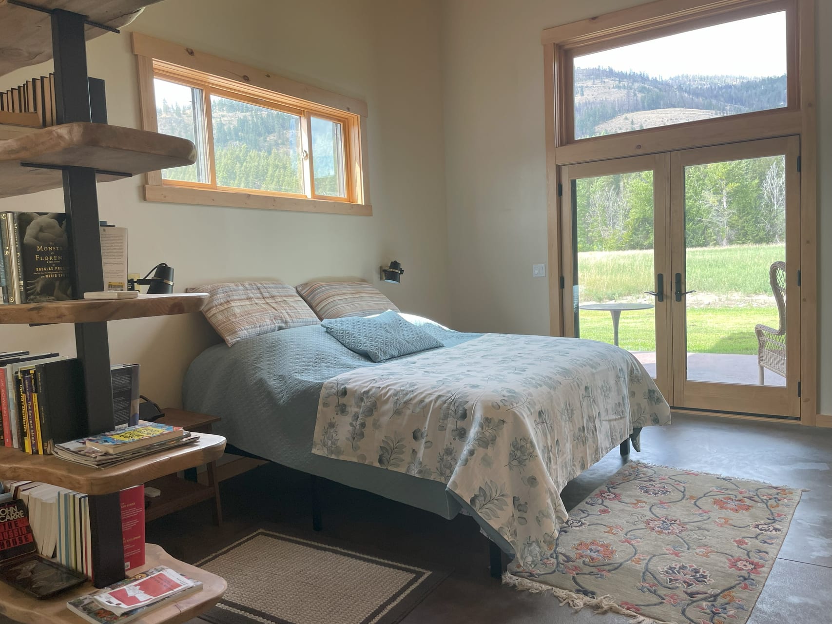 Master suite with queen bed, bookshelf room divider, and French doors to mountain meadow