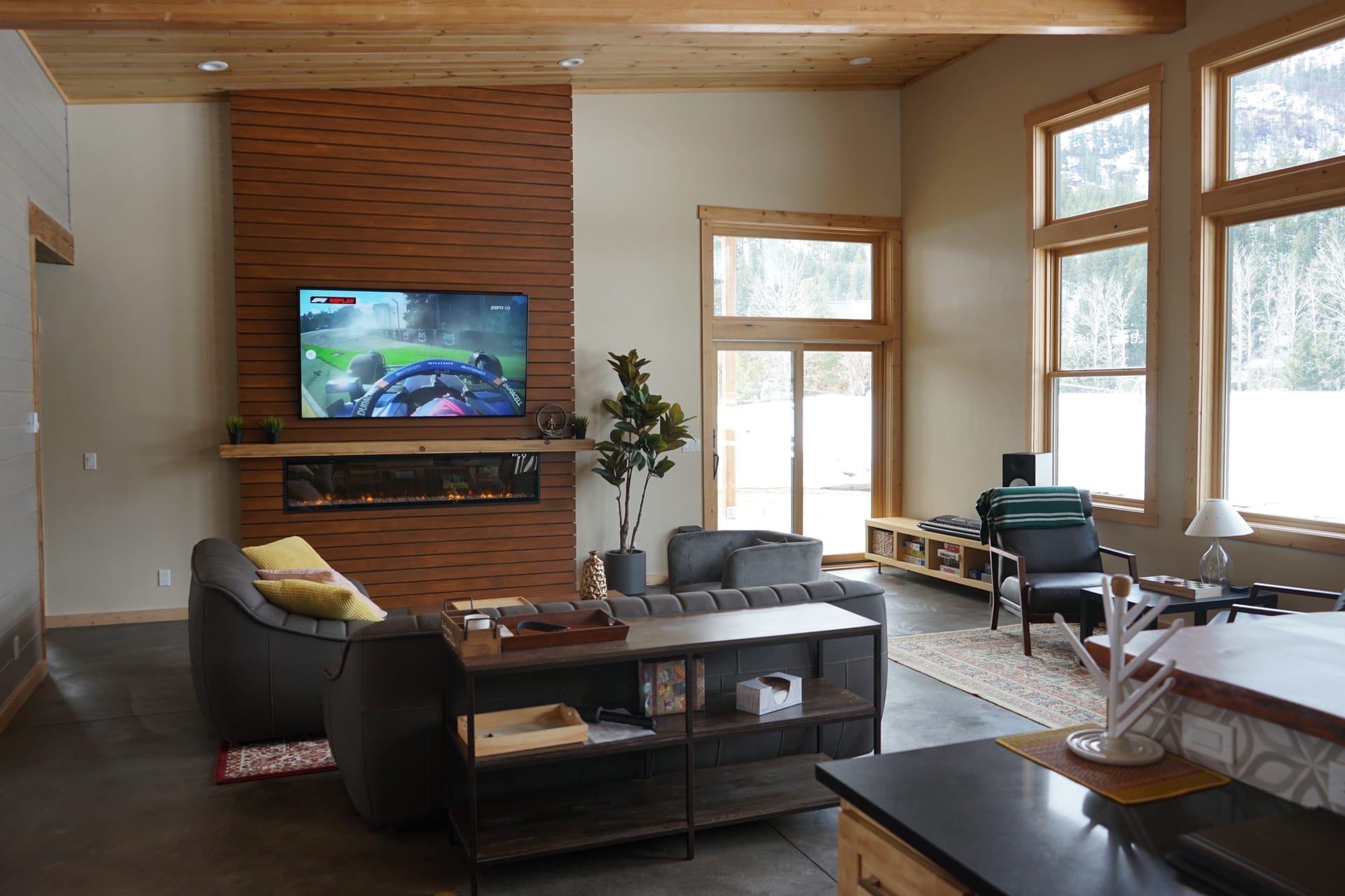 Slatted wood fireplace wall with linear fireplace and TV, mountain windows alongside