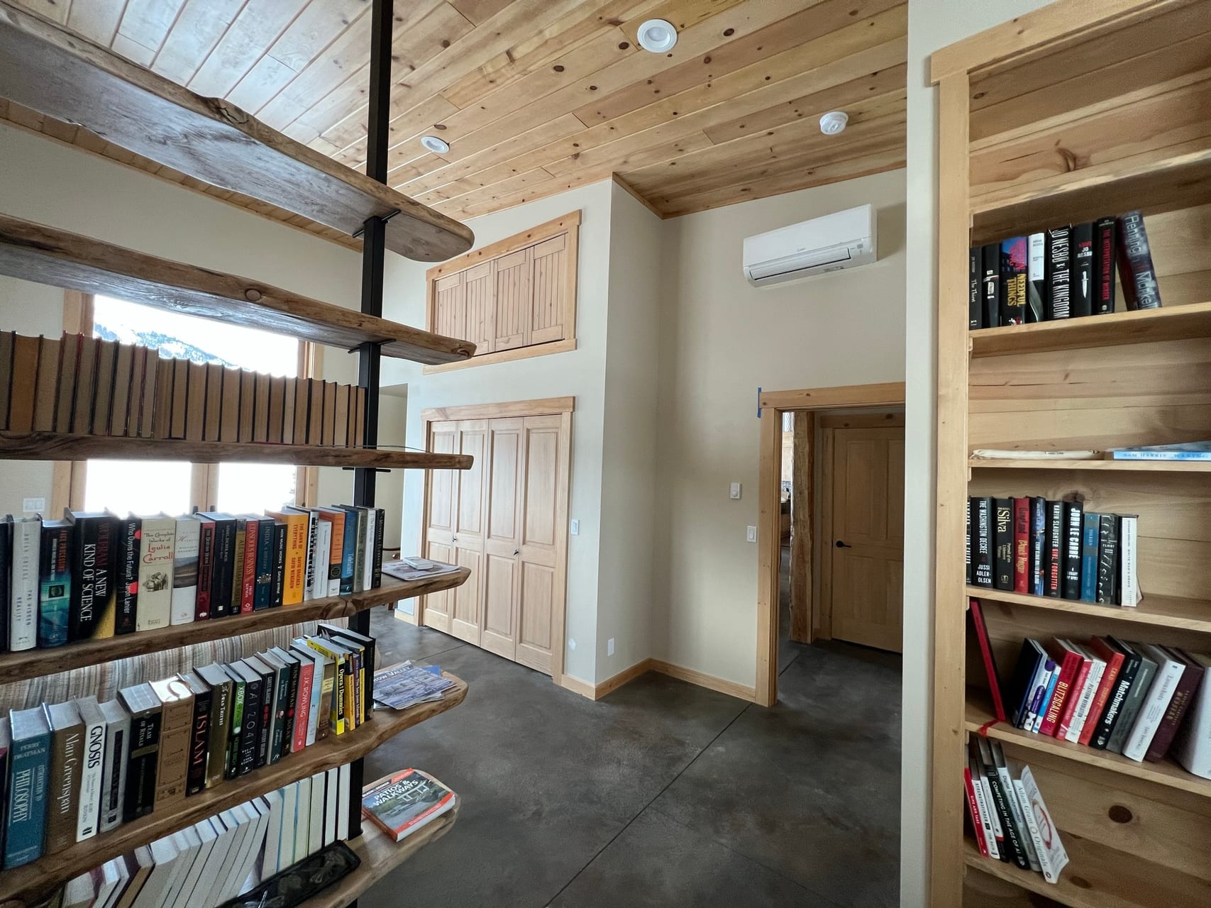 Library hallway with two full-height bookshelves and pine ceiling