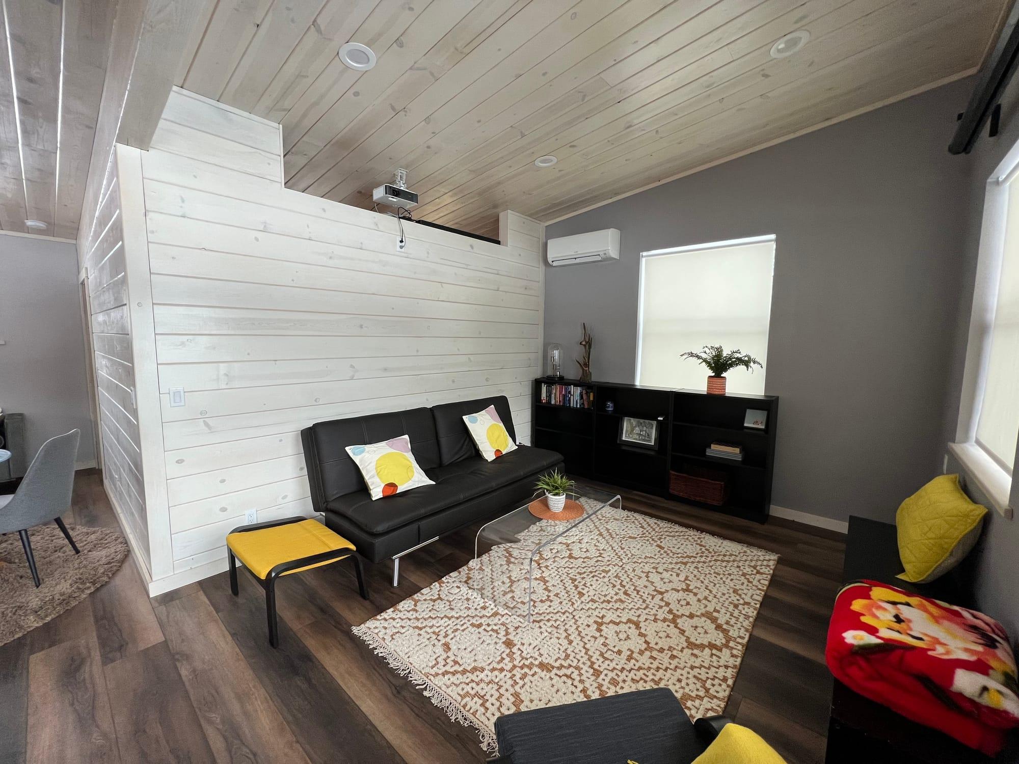 The apartment living and dining area, with the whitewashed shiplap partition and vaulted pine ceiling