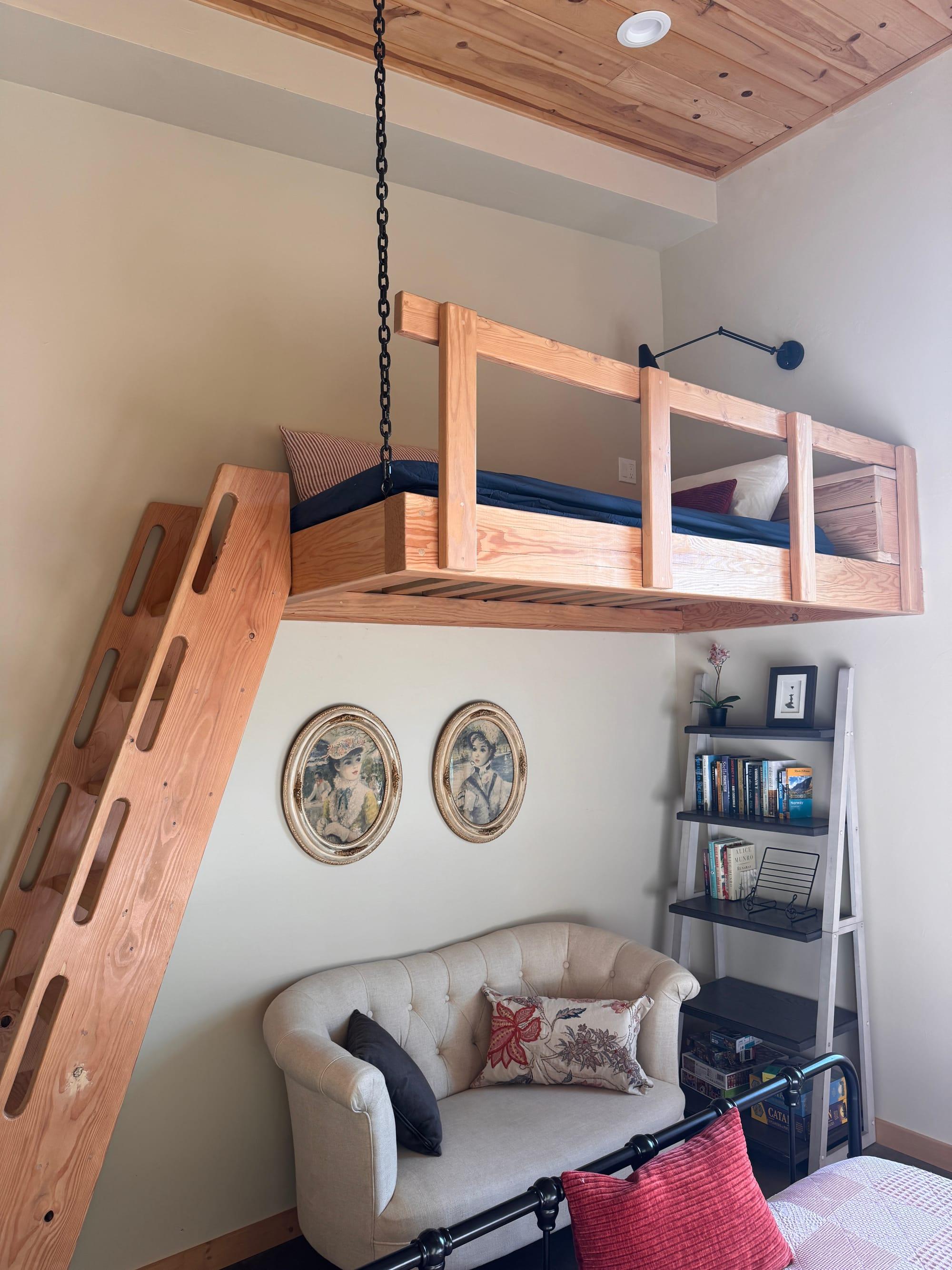 The bunk room: a suspended timber loft bunk reached by a custom ladder, with a reading corner beneath